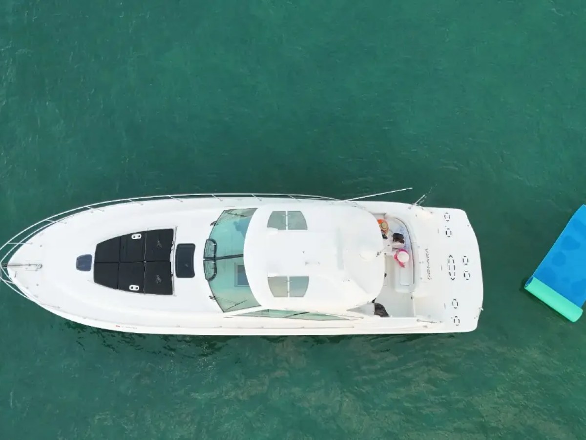 Top view of a white yacht on clear water with a blue raft nearby.