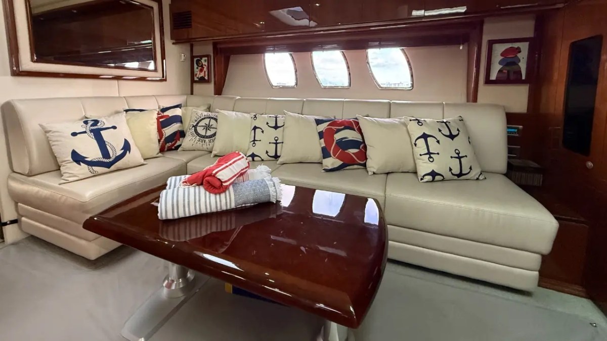 Nautical-themed sofa with decorative anchor pillows and folded towels on a glossy coffee table.