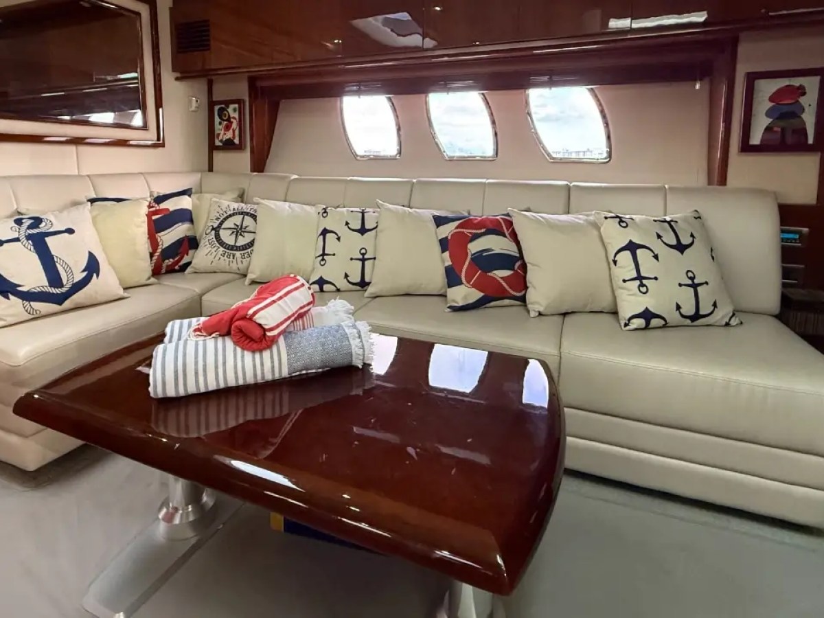 Nautical-themed sofa with decorative anchor pillows and folded towels on a glossy coffee table.