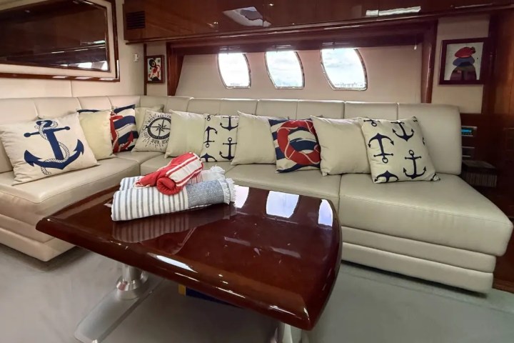 Nautical-themed sofa with decorative anchor pillows and folded towels on a glossy coffee table.