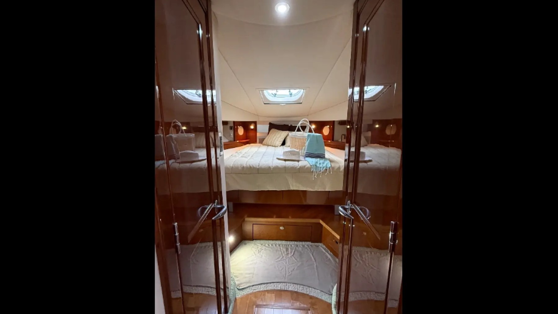 Luxurious yacht cabin interior with a double bed, mirrors, and ambient lighting.