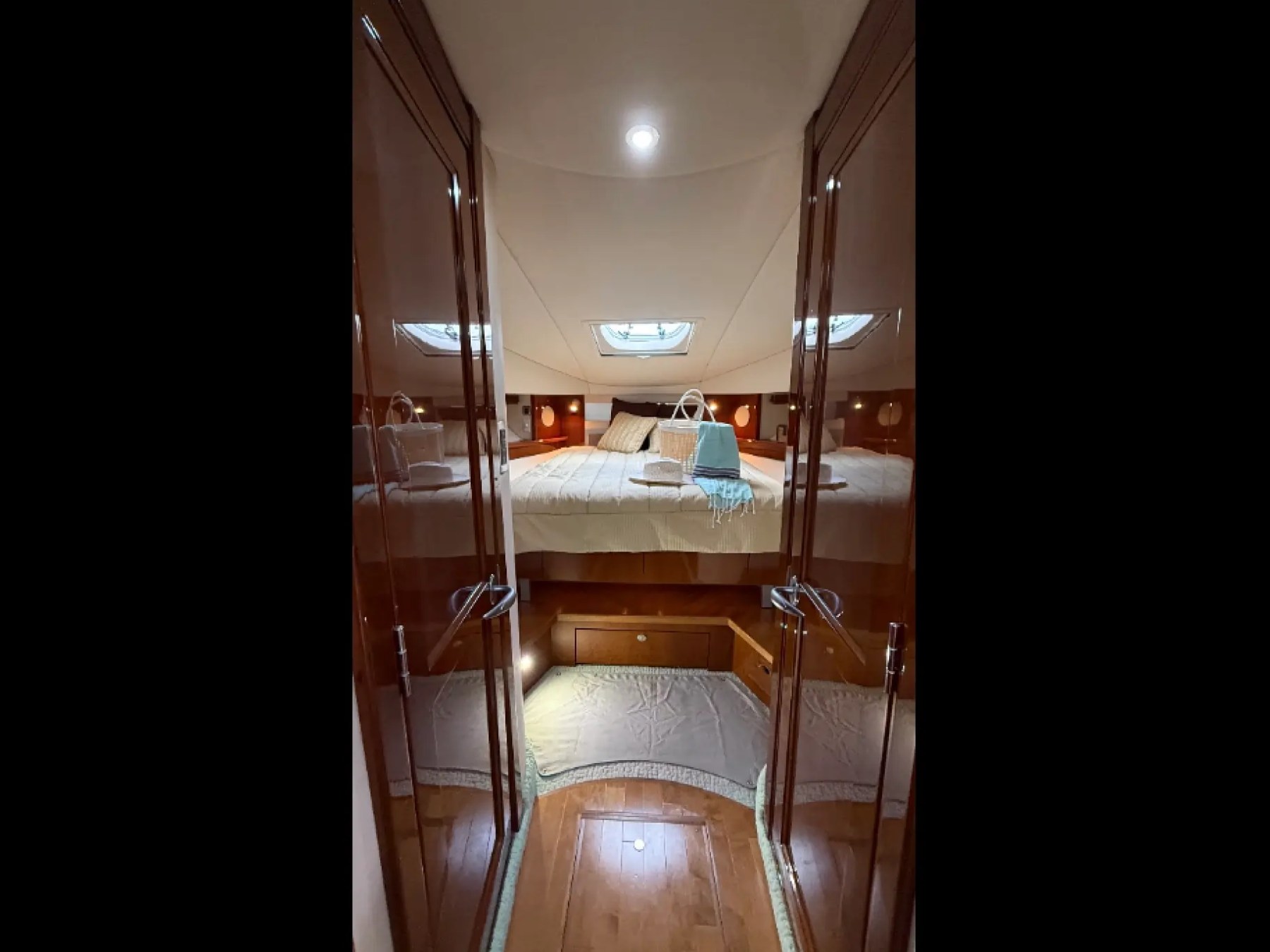 Luxurious yacht cabin interior with a double bed, mirrors, and ambient lighting.