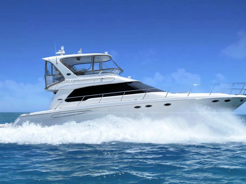 White yacht cruising on blue ocean with clear sky above.