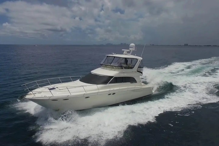 Large white yacht cruising on open water under a cloudy sky.