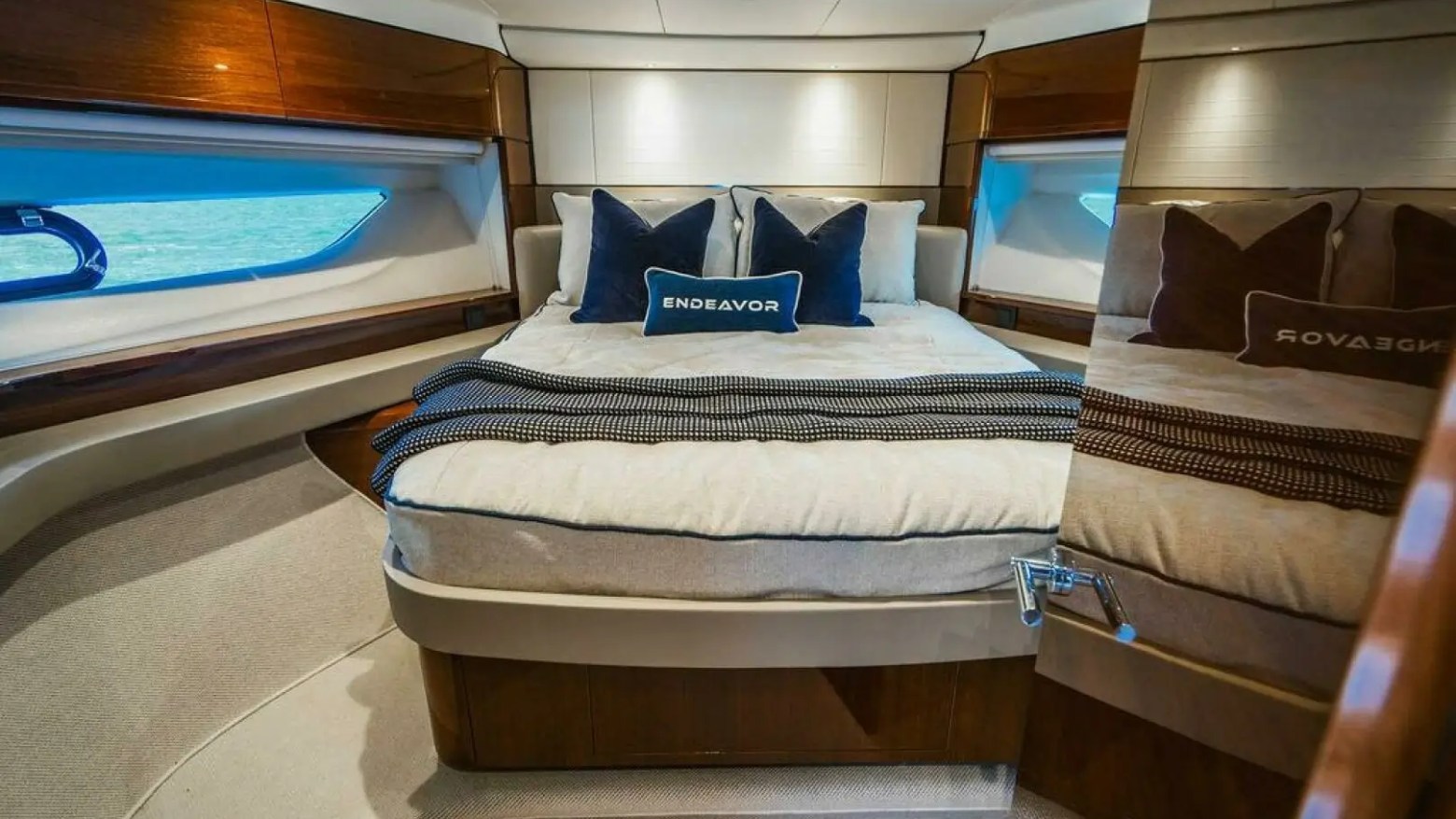 Luxurious yacht bedroom with a large bed, pillows, and a mirror reflecting the room, featuring warm wood accents.