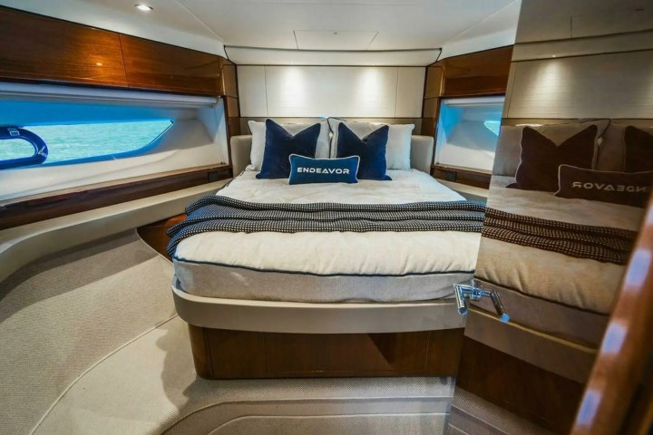 Luxurious yacht bedroom with a large bed, pillows, and a mirror reflecting the room, featuring warm wood accents.