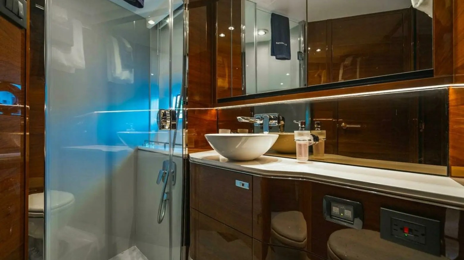 Modern yacht bathroom with glass shower, vessel sink, and mirrored cabinets.