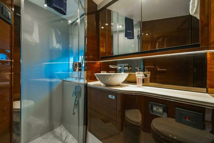 Modern yacht bathroom with glass shower, vessel sink, and mirrored cabinets.