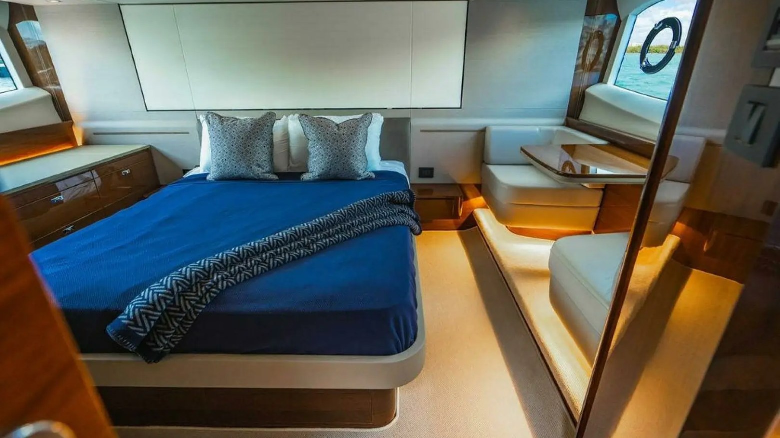 Luxurious boat cabin with a blue bedspread, pillows, and wood furnishings.