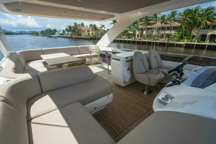 Luxury boat deck with beige seating, table, and view of waterfront homes.