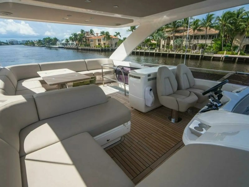 Luxury boat deck with beige seating, table, and view of waterfront homes.