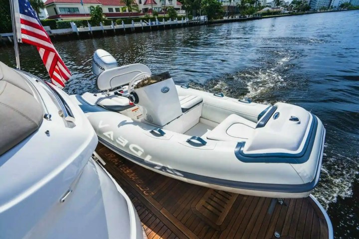 Small inflatable boat with motor on lake, American flag and buildings in background.
