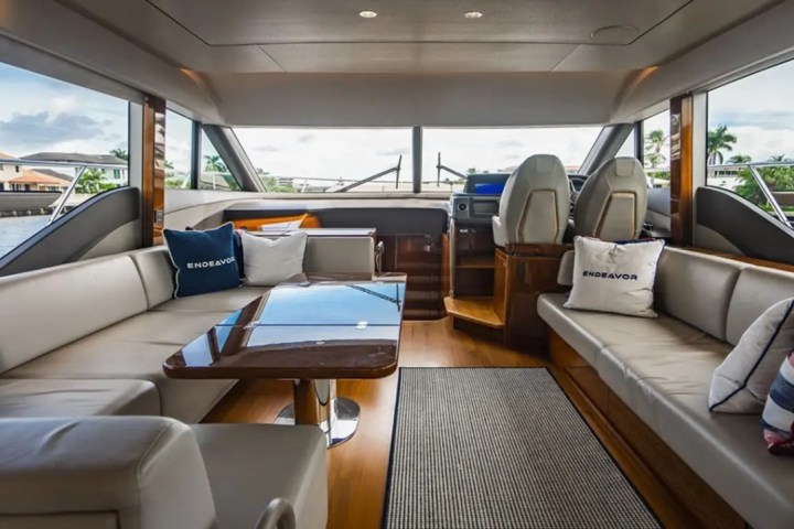 Interior of a yacht with beige seating, table, and helm view.