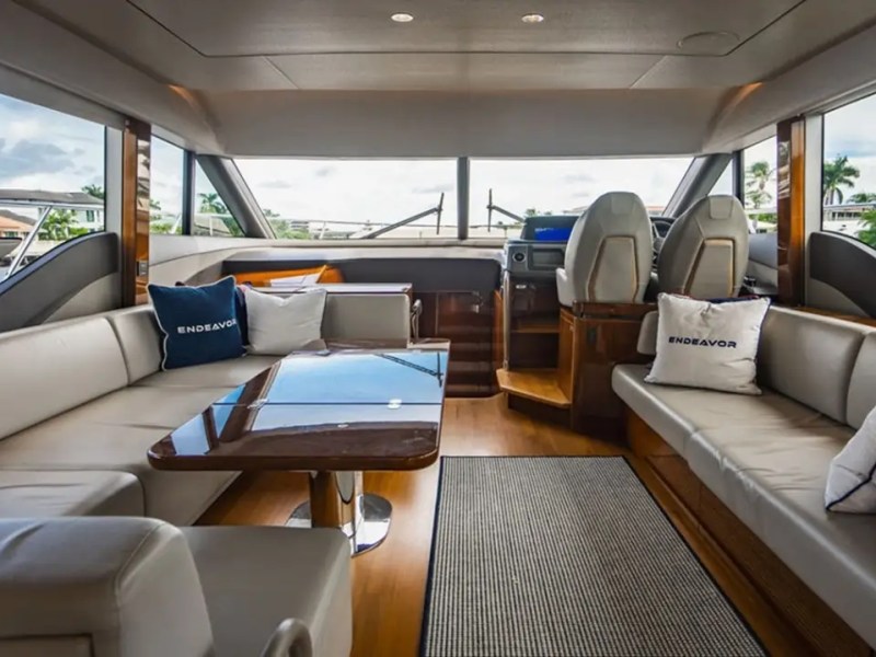 Interior of a yacht with beige seating, table, and helm view.