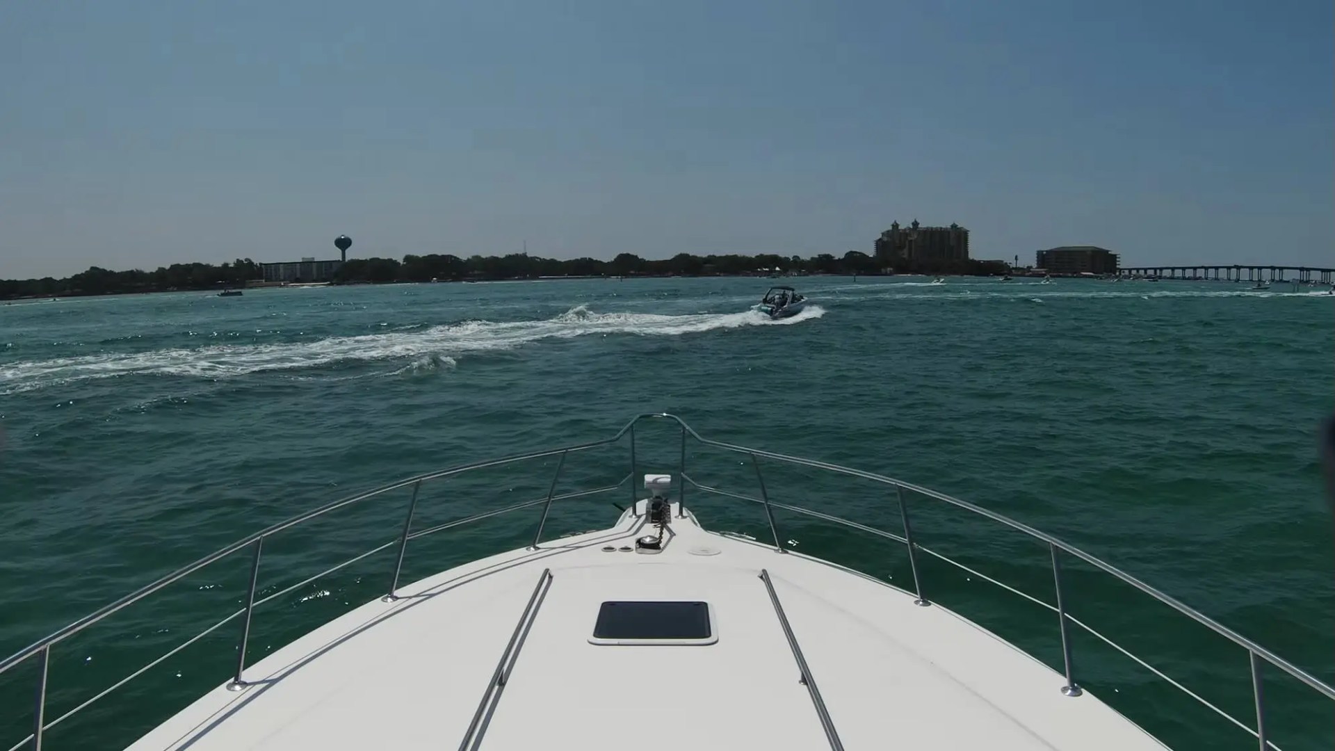 View from a boat's bow on a sunny day with another boat in the distance on the water.
