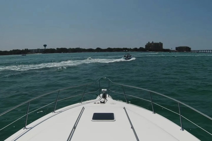 View from a boat's bow on a sunny day with another boat in the distance on the water.