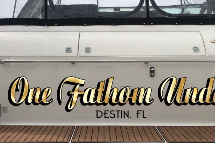 Boat stern with 'One Fathom Under' and 'Destin, FL' in bold letters.