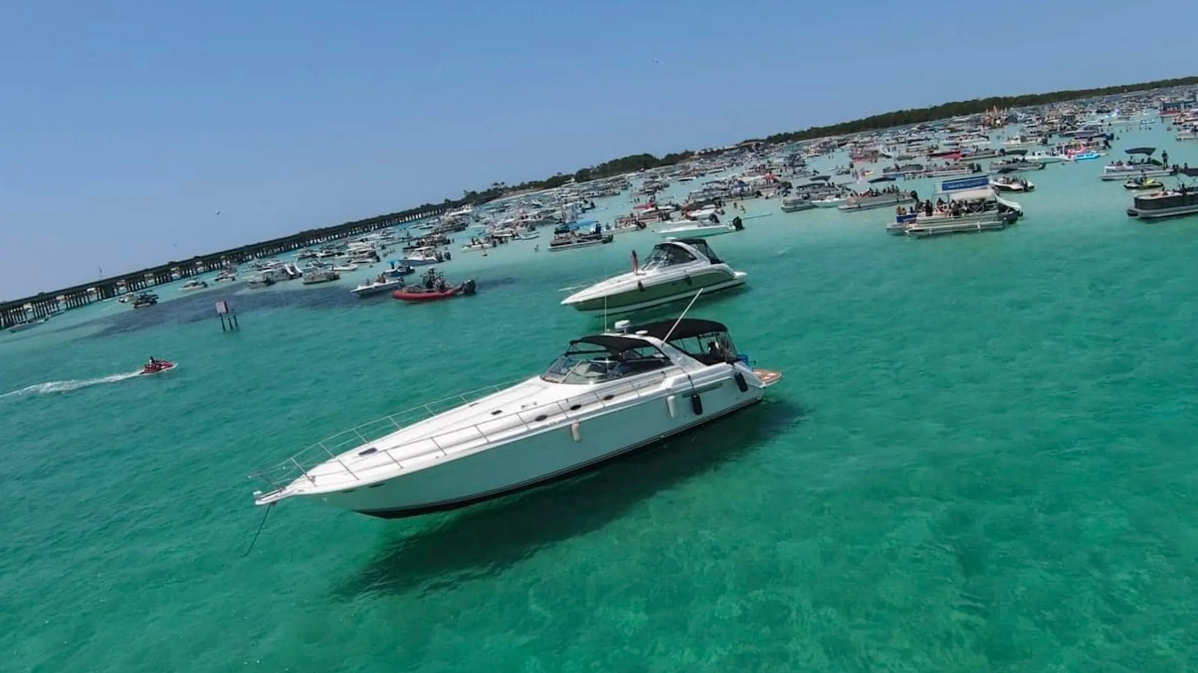 Boats anchored in clear turquoise water on a sunny day with people enjoying the scene.