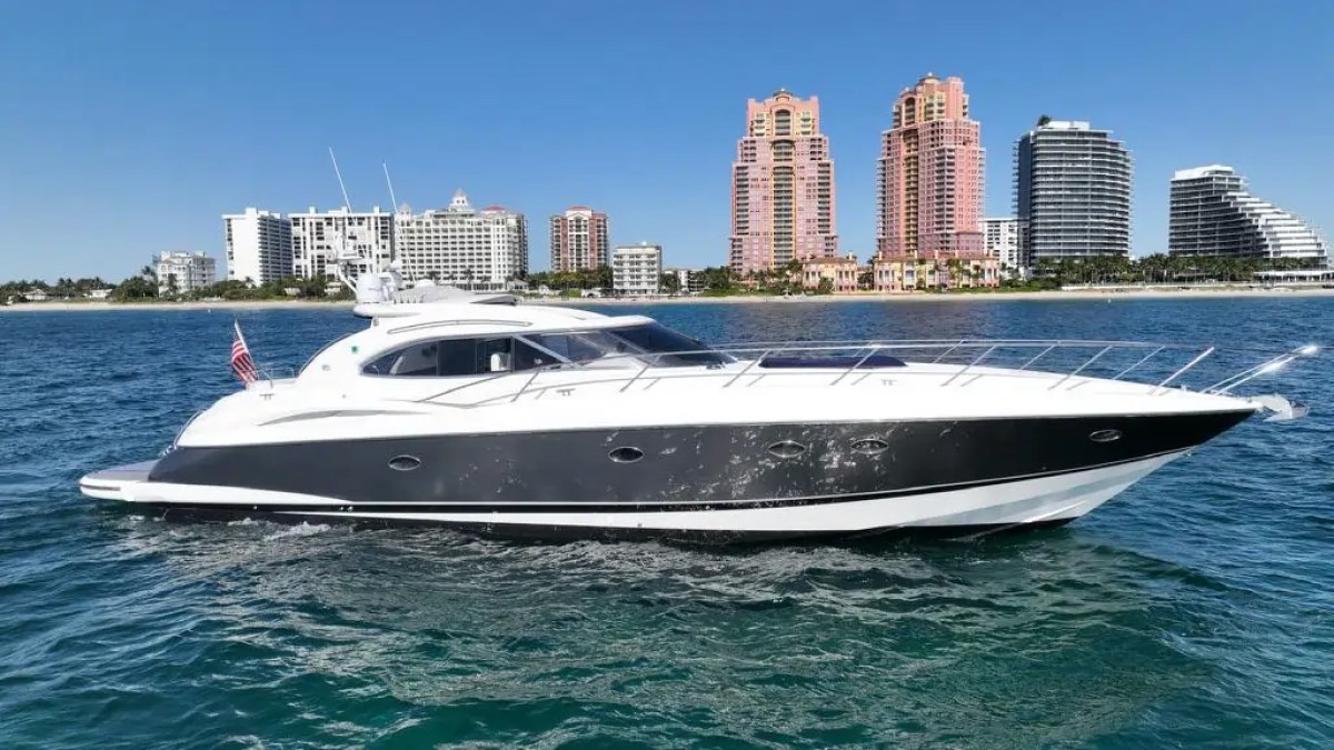 Luxury yacht cruising near a city skyline with tall buildings.