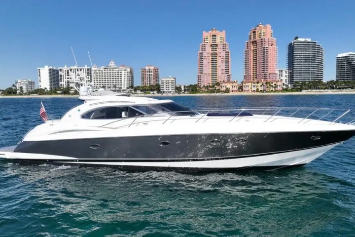 Luxury yacht cruising near a city skyline with tall buildings.