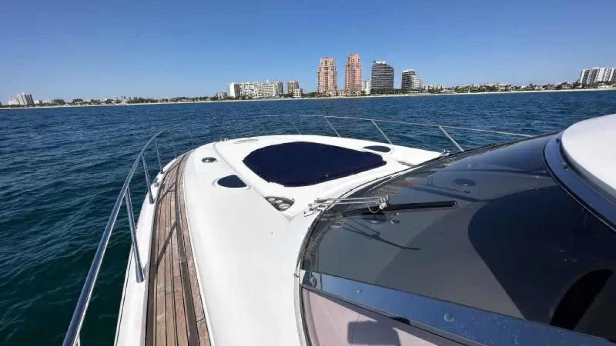 View from a yacht deck overlooking a calm sea with city skyline in the distance.