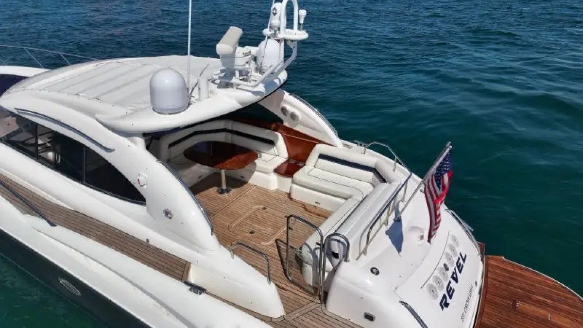 Luxury yacht with sun deck and American flag on calm blue water.