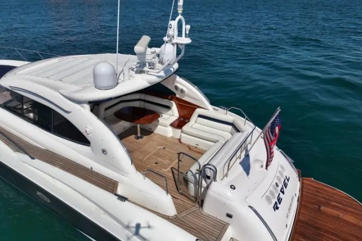 Luxury yacht with sun deck and American flag on calm blue water.
