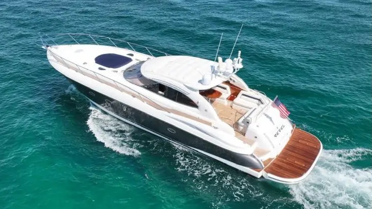 A luxury yacht cruising on clear blue water, viewed from above.