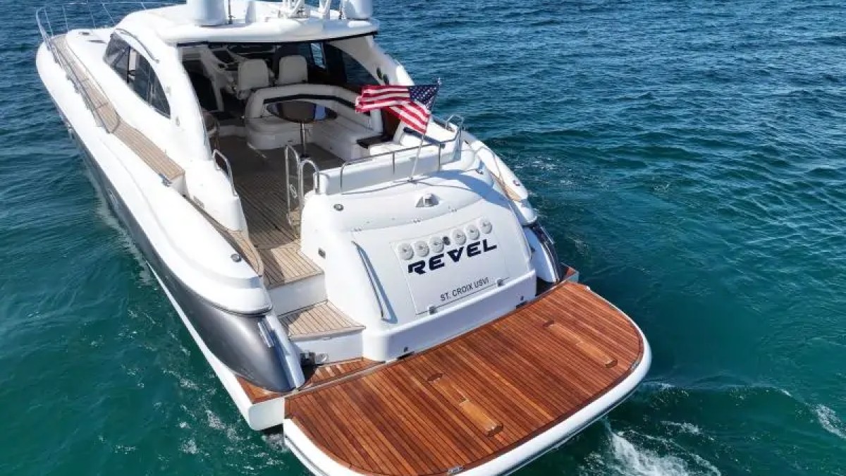 Luxury yacht with wooden deck, American flag, and name 'REVEL' on the water.