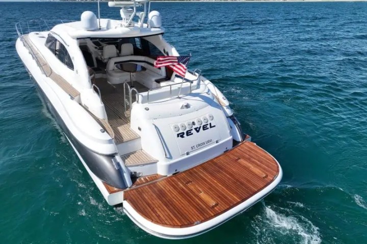Luxury yacht with wooden deck, American flag, and name 'REVEL' on the water.