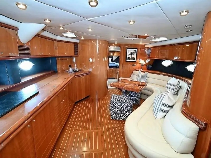 Luxurious yacht interior with wooden paneling, sofas, pillows, and ambient lighting.