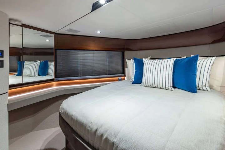 Modern bedroom with a large bed, blue and striped pillows, wood paneling, and mirrored wall.