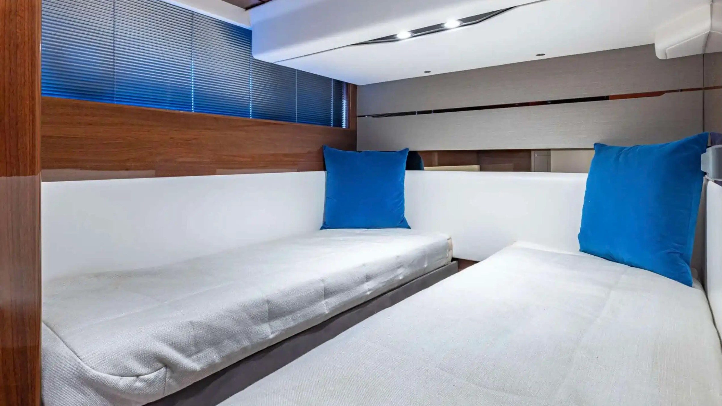 Compact room interior with two single beds, blue cushions, and wood paneling.