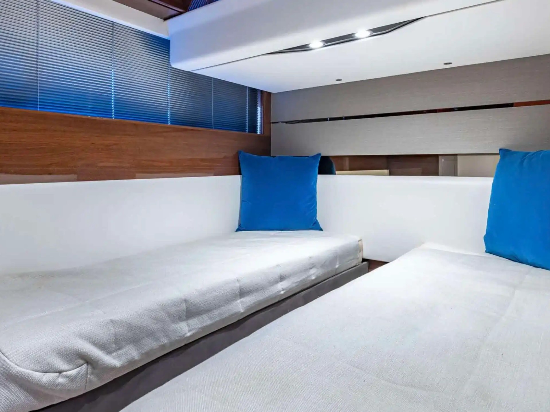 Compact room interior with two single beds, blue cushions, and wood paneling.