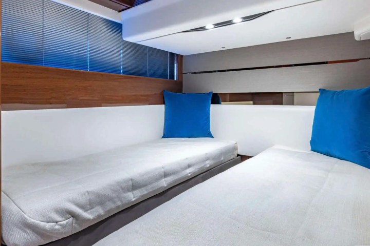 Compact room interior with two single beds, blue cushions, and wood paneling.