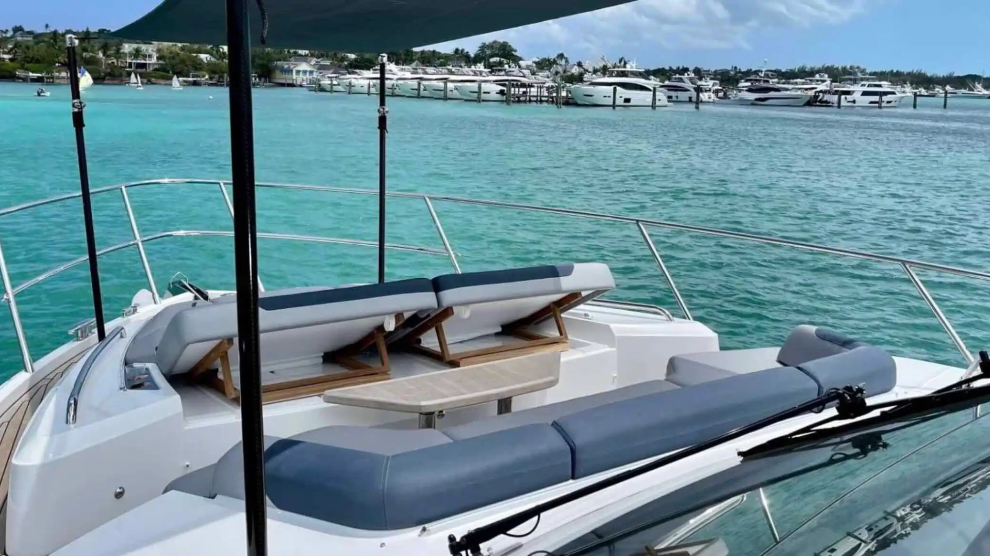 Luxury yacht deck with chairs overlooking turquoise sea and distant yachts.
