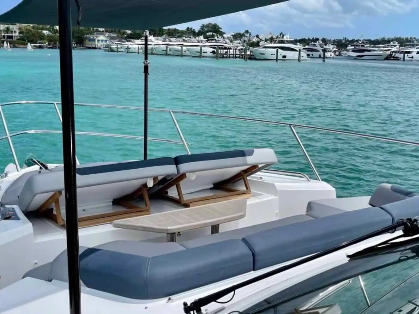Luxury yacht deck with chairs overlooking turquoise sea and distant yachts.