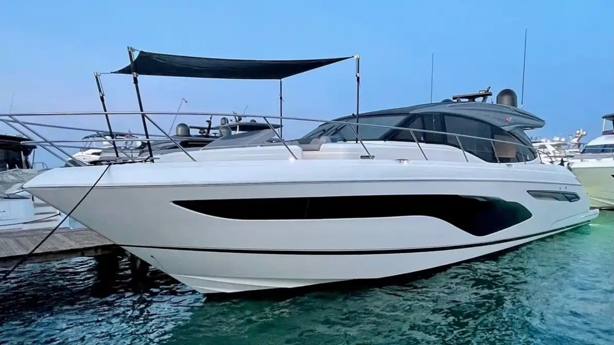 Large white luxury yacht moored at a dock on a calm blue lake.