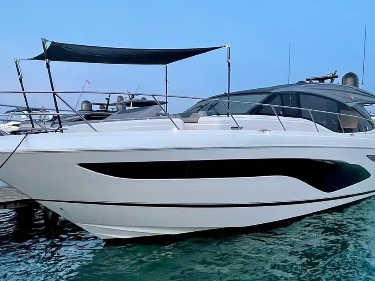 Large white luxury yacht moored at a dock on a calm blue lake.