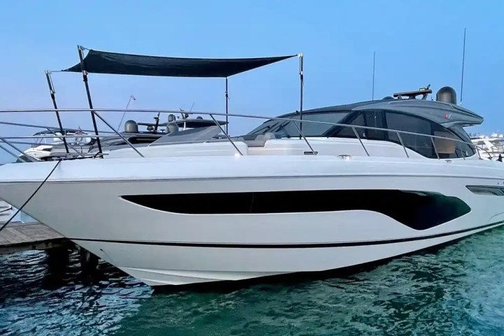 Large white luxury yacht moored at a dock on a calm blue lake.