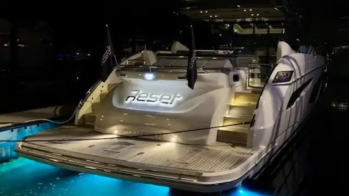 Luxury yacht named 'Reset' with illuminated steps and blue underwater lights at night.