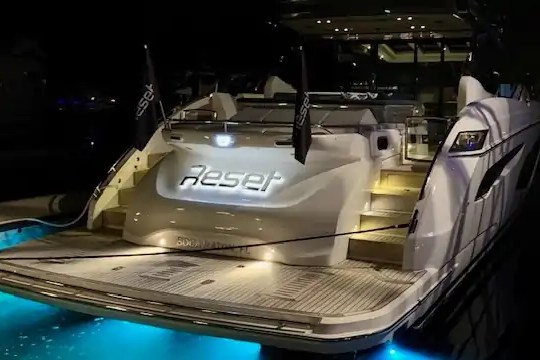 Luxury yacht named 'Reset' with illuminated steps and blue underwater lights at night.