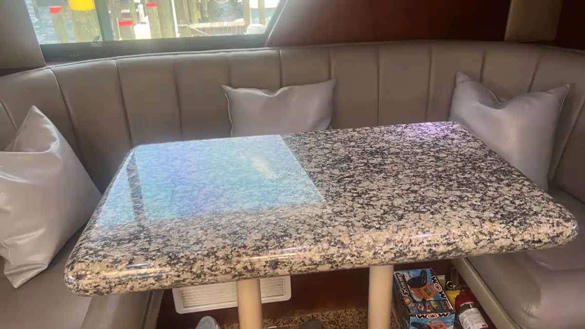Granite table with cushioned seating and pillows on a boat interior.