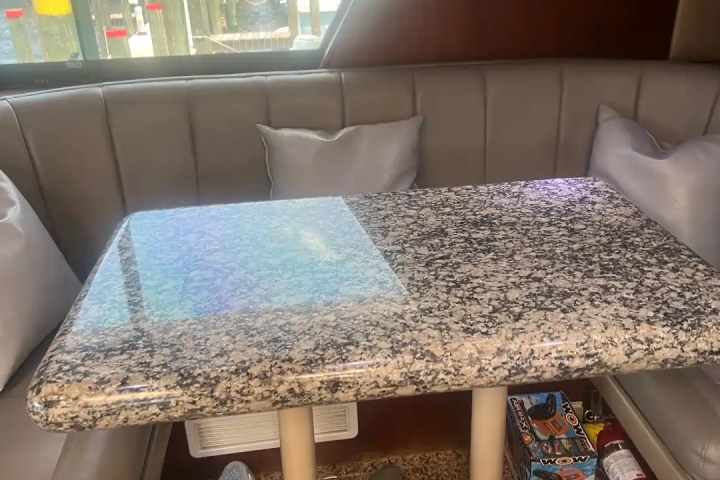 Granite table with cushioned seating and pillows on a boat interior.