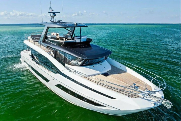 Luxury yacht cruising on calm green waters under a clear sky.