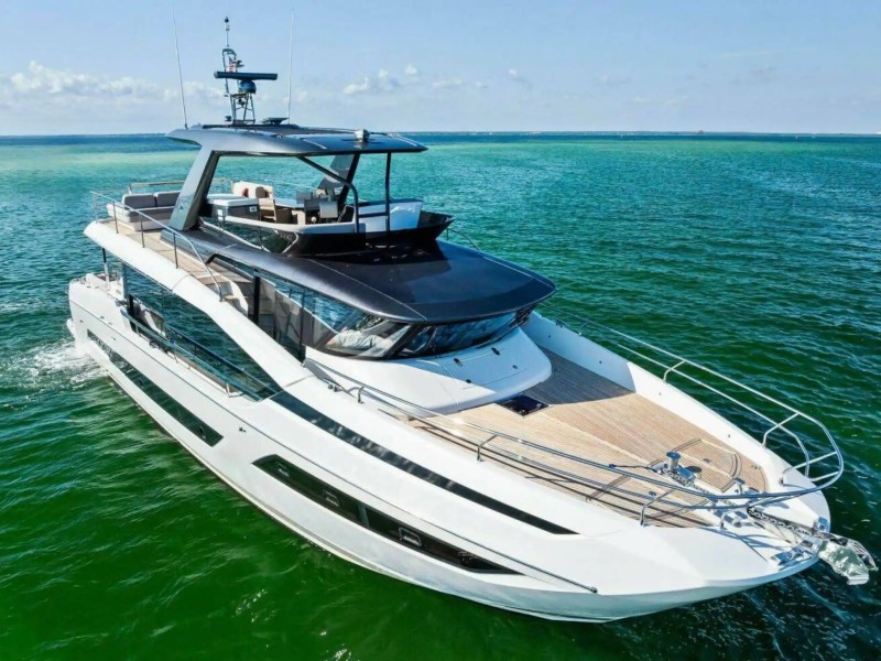 Luxury yacht cruising on calm green waters under a clear sky.