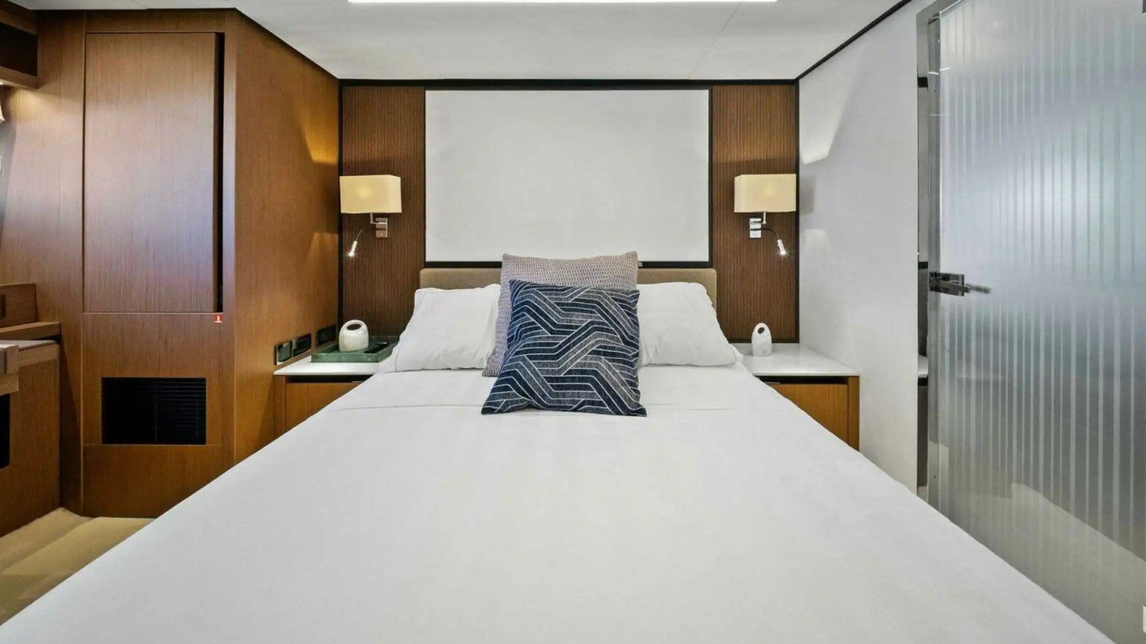 Modern bedroom with a double bed, wood accents, and wall lamps on each side.