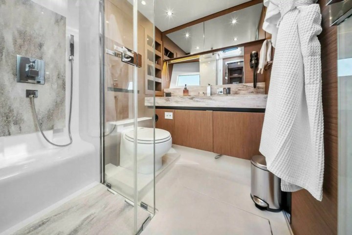 Modern bathroom with glass shower, wood cabinets, and wall mirror.