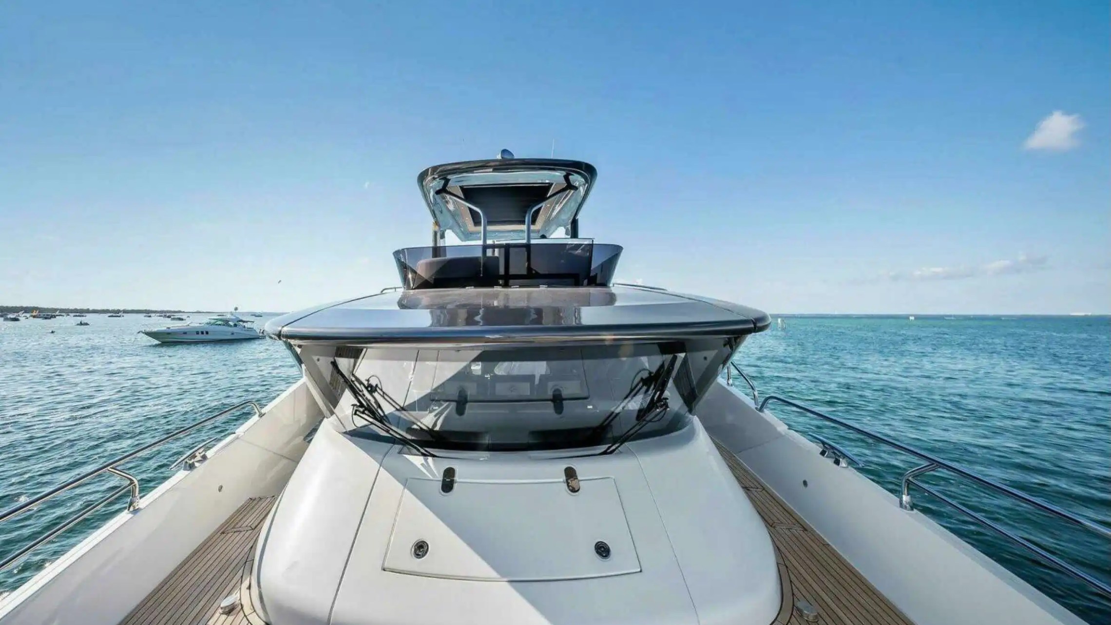 View from yacht deck overlooking ocean with clear blue sky and distant boats.