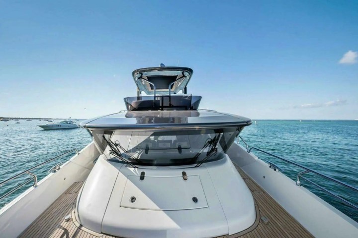 View from yacht deck overlooking ocean with clear blue sky and distant boats.